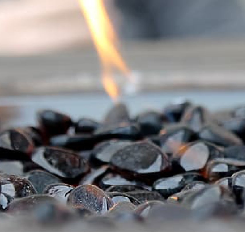 Close-up of black rocks at the bottom of a fireplace that’s using ethanol fuel. 